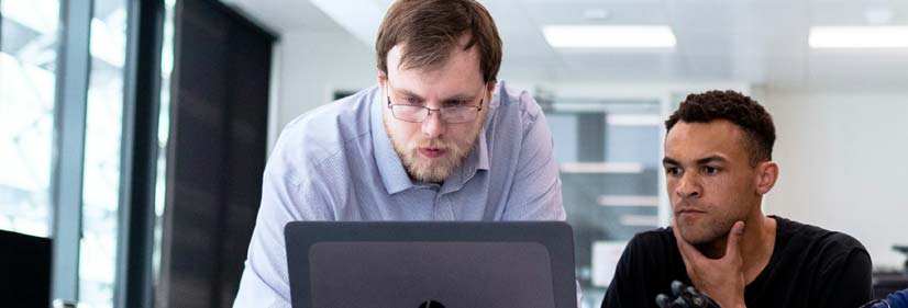 Two people both looking at a laptop